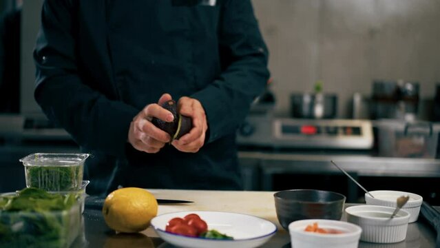 close up in a professional kitchen chef in a black jacket prepares avocado for toast with salmon