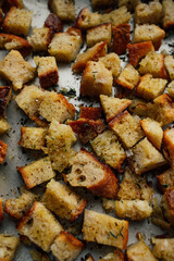 cubes of stale sourdough bread with olive oil and herbs on baking sheet to make croutons