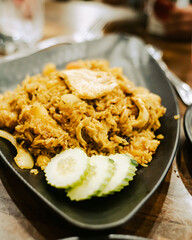 Tone photo Thai style green chicken curry with fried rice, nuts, cucumber slices served on wooden bowl at upscale Thai restaurant in Austin, Texas, healthy signature Asian food lunch dinner dish