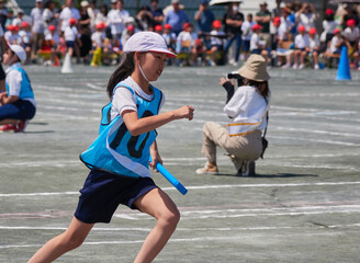 小学校の運動会の学生たちのリレーの走る姿