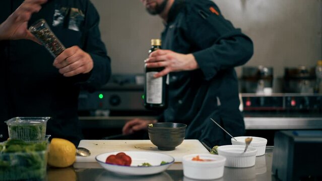 close up in a professional kitchen chef in a black jacket prepares avocado for toast with salmon