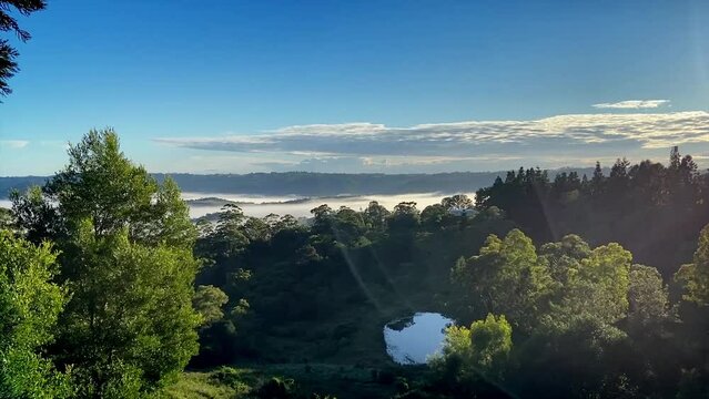 Breath taking dawn sunrise in the Sunshine Coast Hinterland at Maleny, Queensland with fog ebbing away through the valley as the sun comes up illuminating the drifting fog