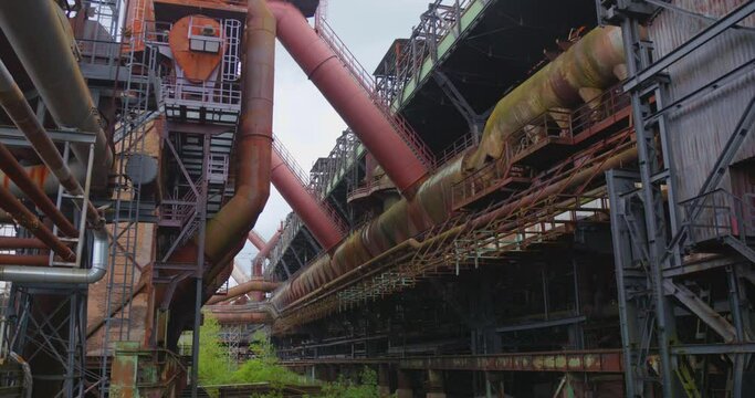 Industrial ironworks structure with pipes in deserted factory complex.