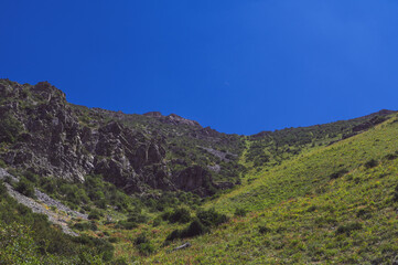 Rocky mountains with green grass under a blue sky in summer