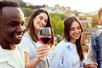 Young group of friends enjoying summer party at night. Millennial people having fun while dancing and feeling happy at celebration at home terrace.