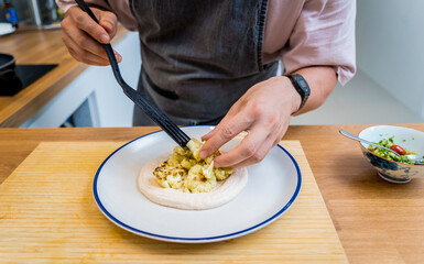Chef at the kitchen preparing bean porridge with cauliflower and vegetables