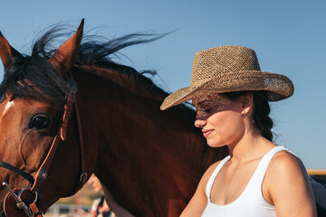 Woman taking care of his brown horse in an equestrian center