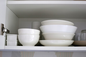 Clean dishes and tableware on a white shelf