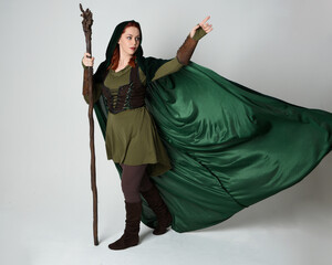 Full length portrait of red haired female model wearing green medieval fantasy costume leather...