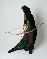 Full length portrait of red haired female model wearing green medieval fantasy costume leather...