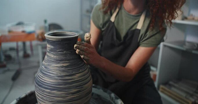 Young woman shapes clay on pottery wheel to make clay bowl, handmade creative artist