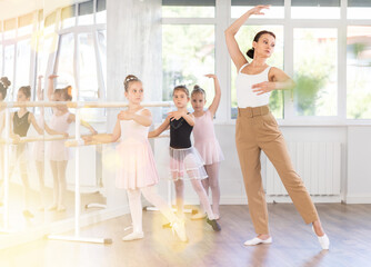 Female teacher dancer performing pirouette in front of class