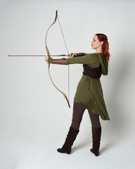 Full length portrait of red haired female model wearing green medieval fantasy costume, leather...