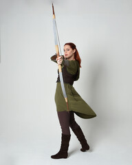 Full length portrait of red haired female model wearing green medieval fantasy costume, leather...
