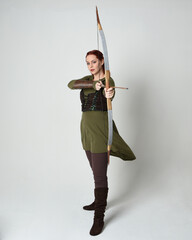 Full length portrait of red haired female model wearing green medieval fantasy costume, leather...