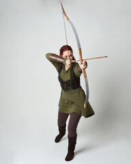Full length portrait of red haired female model wearing green medieval fantasy costume, leather...