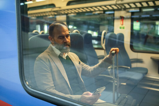 Mature businessman using smartphone on a train