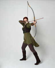 Full length portrait of red haired female model wearing green medieval fantasy costume, leather...