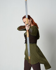 close up portrait of red haired female model wearing green medieval fantasy costume, leather...