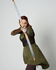close up portrait of red haired female model wearing green medieval fantasy costume, leather...