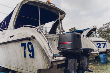 Old and rusty motor boats on a landfill surrounded by tropical forest