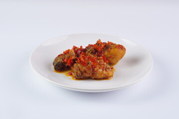 Indonesian typical balado fried chicken on a white plate on a white background with studio lighting