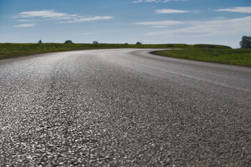 Sunlit winding road through a scenic countryside with blue sky