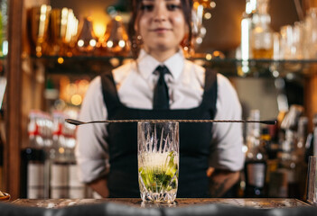 Female bartender preparing a cocktail in a traditional cocktail bar