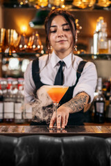 Young female bartender offering a drink