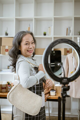 A mature Asian female online seller is live streaming from home, selling her products online.