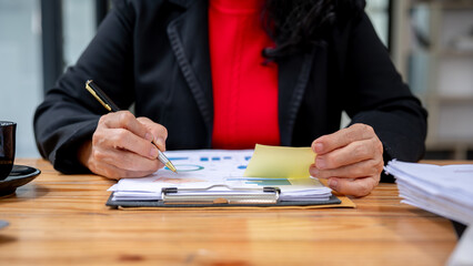 A senior businesswoman examining a business financial graph report, and working in the office.