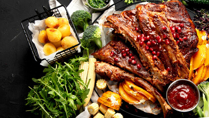 Pork ribs with vegetables on black background. Food for picnic concept