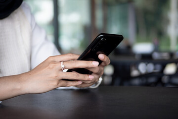 Close up of woman hand using modern smart phone while working in office with computer. and typing a text message on his cell phone.