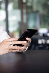 Close up of woman hand using modern smart phone while working in office with computer. and typing a text message on his cell phone.