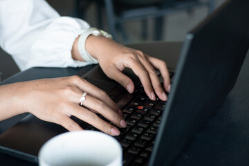Beautiful young woman working on laptop and smiling while sitting outdoors in cafe. Young woman using laptop for work.