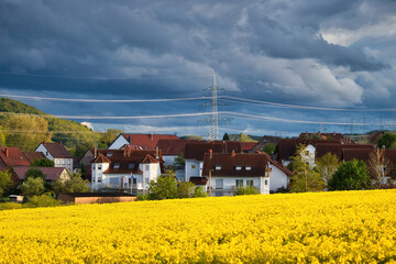 Storm clouds over Lohnsfeld, Germany and sun shining on rapeseed field on a spring evening.