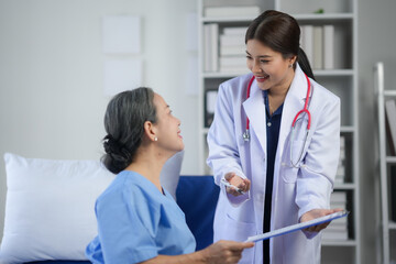 Friendly doctor consulting with a senior patient in a hospital room, discussing treatment and care options with a smile.