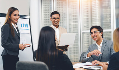 Smiling diverse colleagues gather in boardroom brainstorm discuss financial statistics together