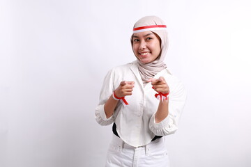 Young asian muslim woman with red white ribbon celebrating Indonesia independence day while pointing at the camera