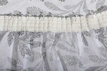 The folds and frills of the patterned curtain. The fabric is thin textured tulle.