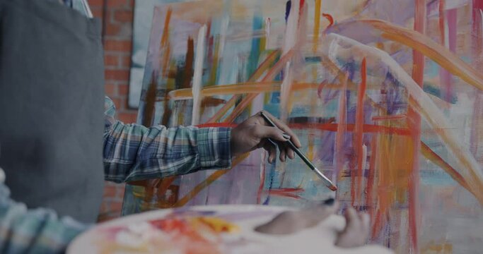 Close-up of anonymous artist hand painting lines on abstract picture creating masterpiece of contemporary art. Culture and person concept.