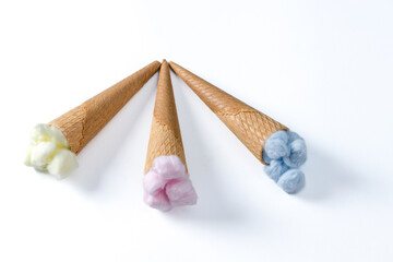 different colored cotton balls in an ice cream cone isolated on a white background