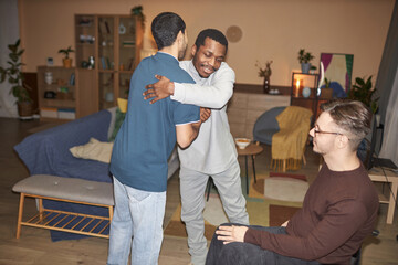 Group of friends embracing and greeting each other during house party shot with flash