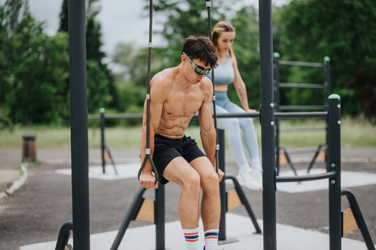 Two athletes engaging in an outdoor calisthenics workout, utilizing parallel bars and rings. Fitness training in a park setting.