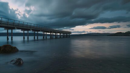 Obraz premium A picturesque pier over clear waters, elegantly framed by a sunset, with the tranquil sea reflecting the colorful sky.
