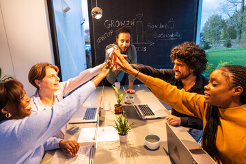 Diverse team celebrating success with highfives in modern office, showing collaboration and achievement