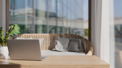 A laptop computer on a minimal wooden coffee table in a beautiful contemporary living room.