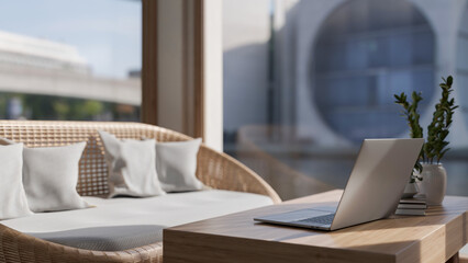 A laptop computer on a minimal wooden coffee table in a beautiful contemporary living room.