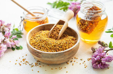 Raw organic bee pollen and honey in jars  and acacia flowers. .