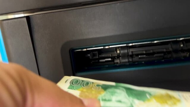 Close-Up of Hand Withdrawing Pakistani Rupees from ATM.